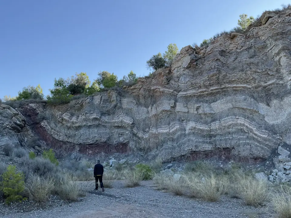 Aflorament de capes de roca plegades amb una persona que en mostra l’escala.