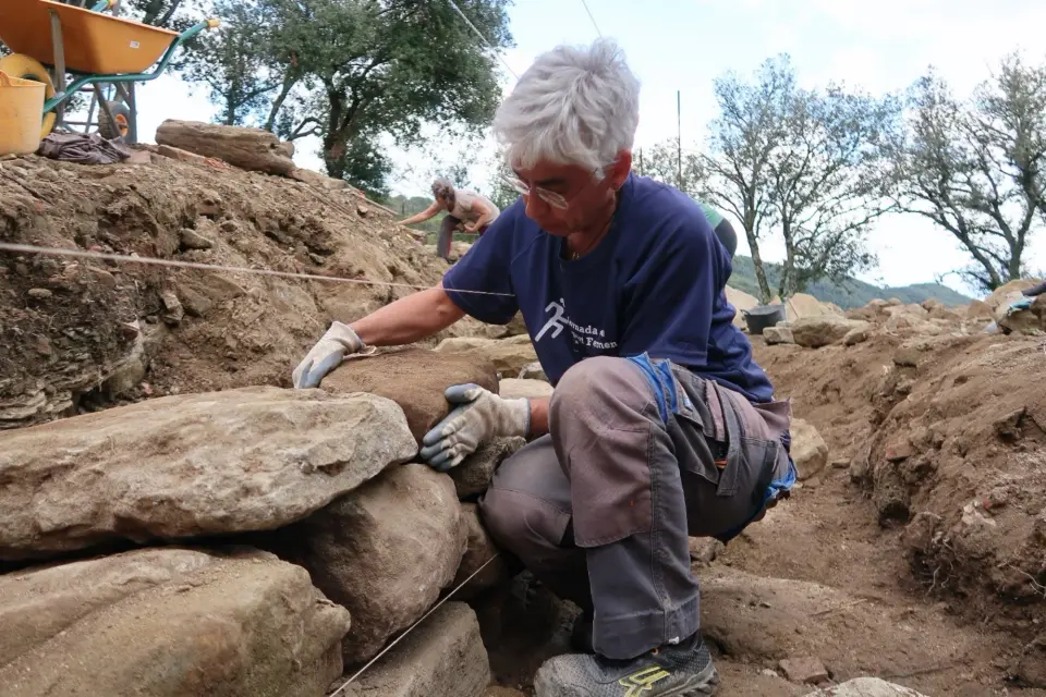 Treballadora col·locant pedres durant la construcció d’un mur de pedra seca.