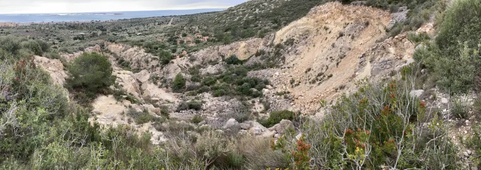 Paisatge erosionat per un barranc profund en un vessant de vegetació baixa.